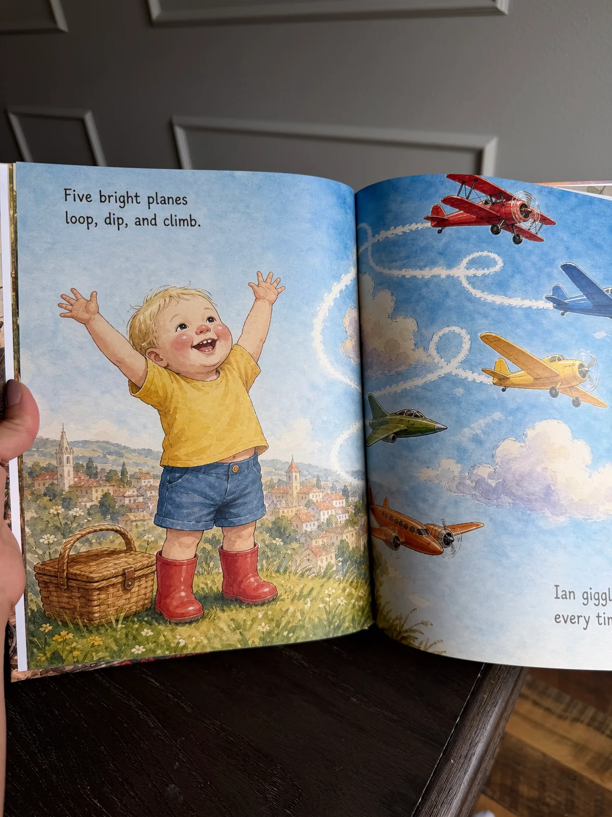 A photograph of Ian's printed counting book, showing his illustrated character and five planes