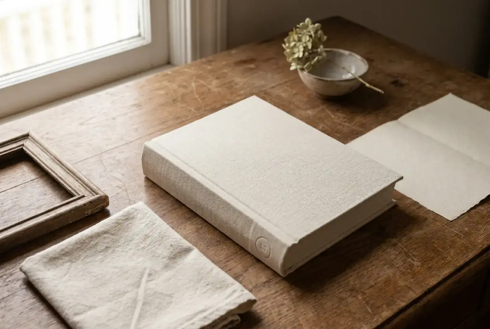 A stack of sundayfawn hardcover storybooks on a cream table — an adventure book open to a illustrated spread, an ABC volume beside it, a milestone-birthday book.